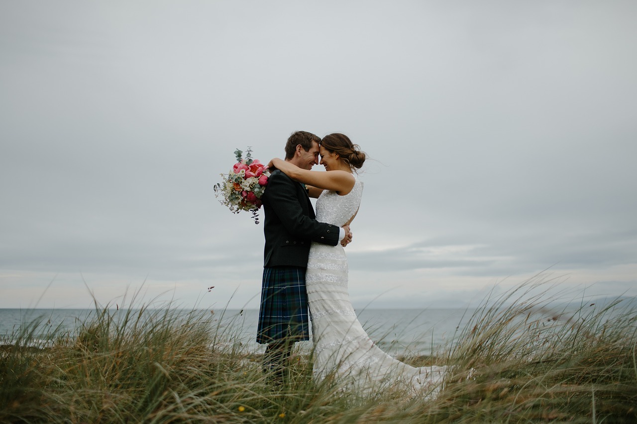 Braut undBräutigam auf einer Wiese im Sand am Meer.